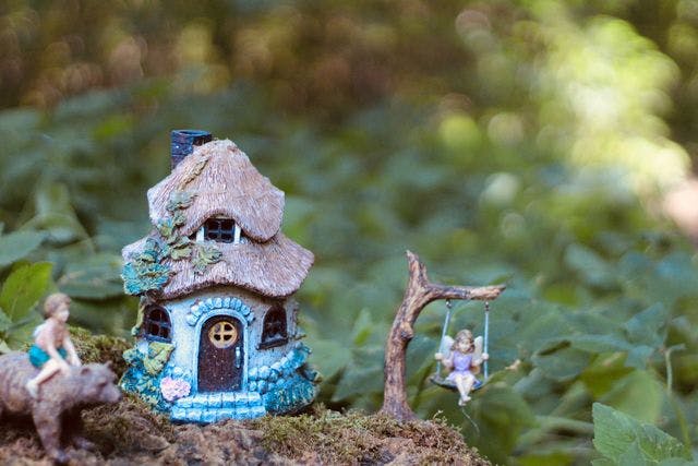 A tiny house and swing with a fairy doll on it
