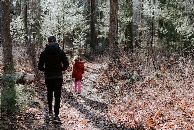 A father and daughter walk a forest trail together